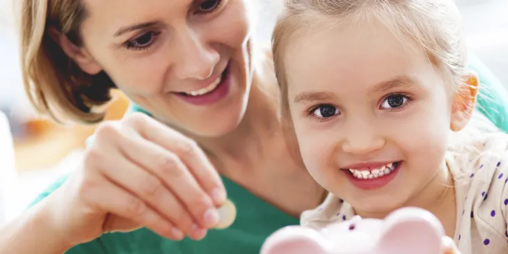 Mother showing child how to save with a piggy-bank.