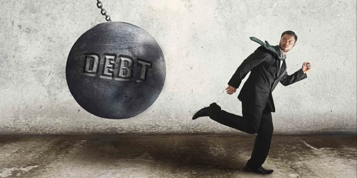 Man running from debt ball swinging on chain