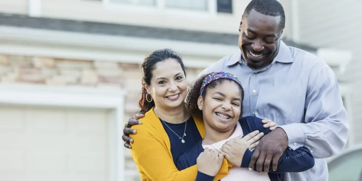 Family smiling in front of home