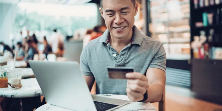 Man Smiling with Credit Card in Cafe