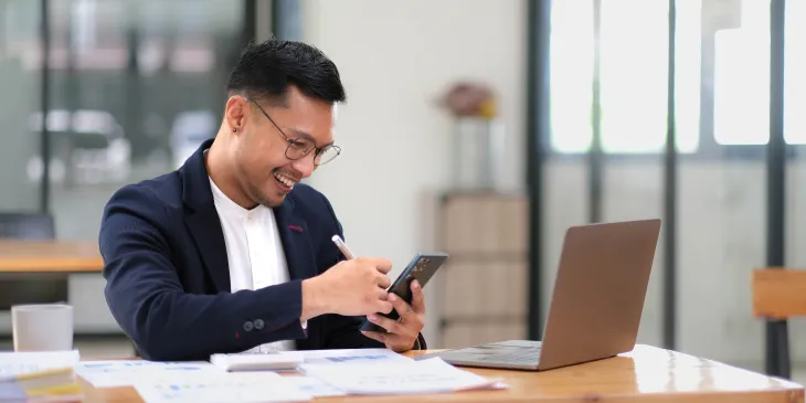 Male business owner looking at iphone - Extraco Banks