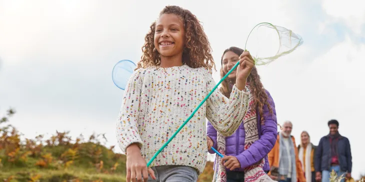 girl in front holding a net with family behind her