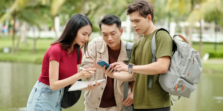 College students looking at phone - Extraco Banks