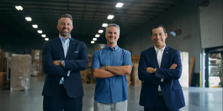 Three men standing next to each other smiling with their arms crossed
