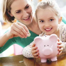 Mother showing child how to save with a piggy-bank.