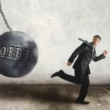 Man running from debt ball swinging on chain