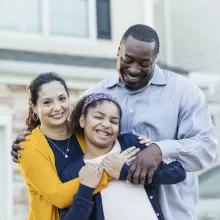 Family smiling in front of home