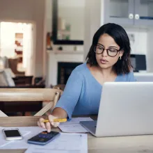 Woman using laptop and calculator