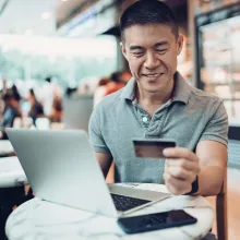 Man Smiling with Credit Card in Cafe