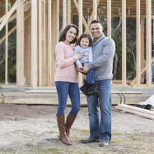 couple and child standing outside of their home construction site