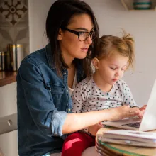 Mom holding daughter and looking at computer